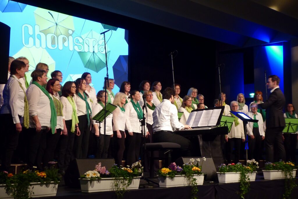 Leicht seitliche Sicht auf die Chorisma-Sängerinnen in Konzert-Outfit, mit den Mündern geöffnet zum Singen.